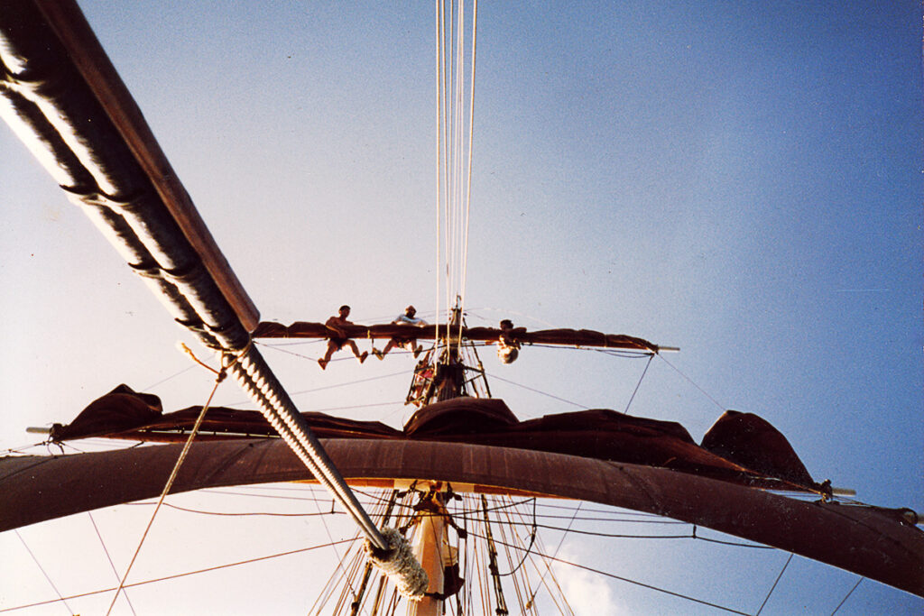 Crew members go aloft to unfurl The Eye of the Wind's sails.