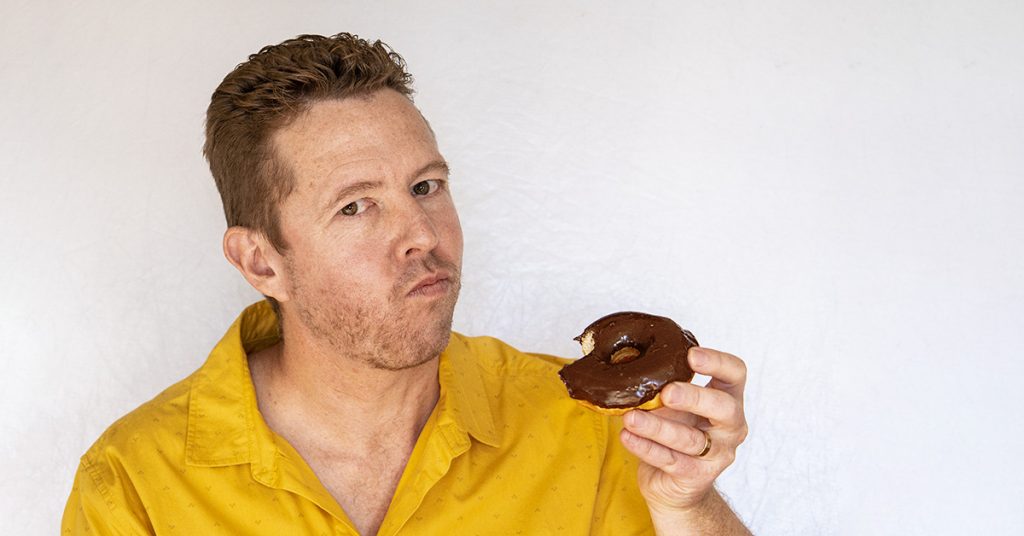 Tim Horan eats a chocolate donut.