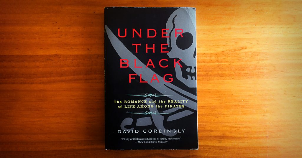 Tim Horan's paperback copy of 'Under the Black Flag' by David Cordingly on his timber dining table.