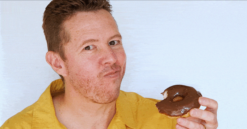 Tim Horan eating a chocolate donut.